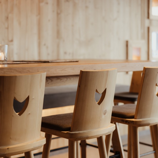 Eleganti sedie in legno nella Stube di pino cembro creano un ambiente accogliente e caloroso per gli ospiti.