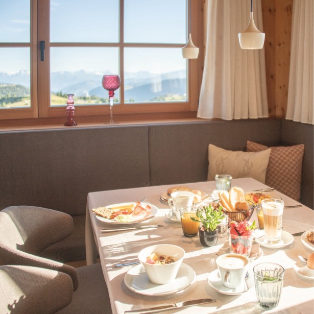 Un tavolo da colazione apparecchiato, illuminato dal sole mattutino che splende attraverso la finestra.