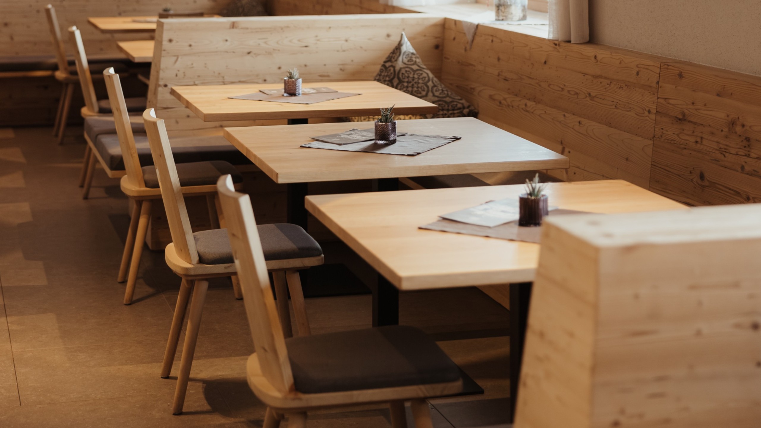 I tavoli e le sedie di legno massello nella sala da pranzo si abbinano al design semplice dell'arredamento.