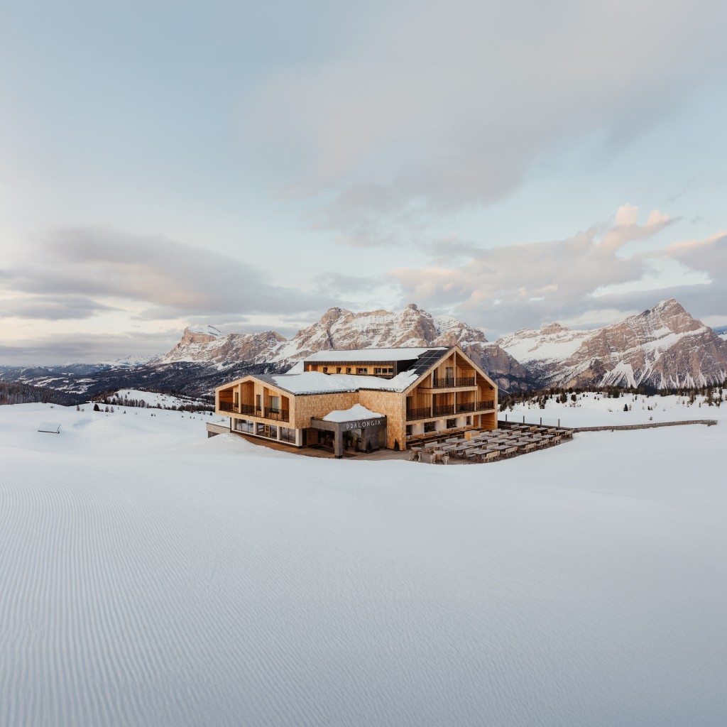 Das neu renovierte Berggasthaus Pralongià im Winter, mit verschneiten Bergen im Hintergrund.