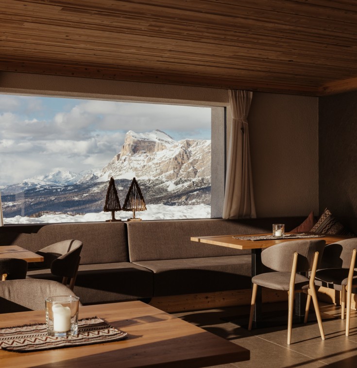 Der schlicht eingerichtete Speisesaal im Berggasthaus Pralongià, mit Aussicht auf die Dolomiten.