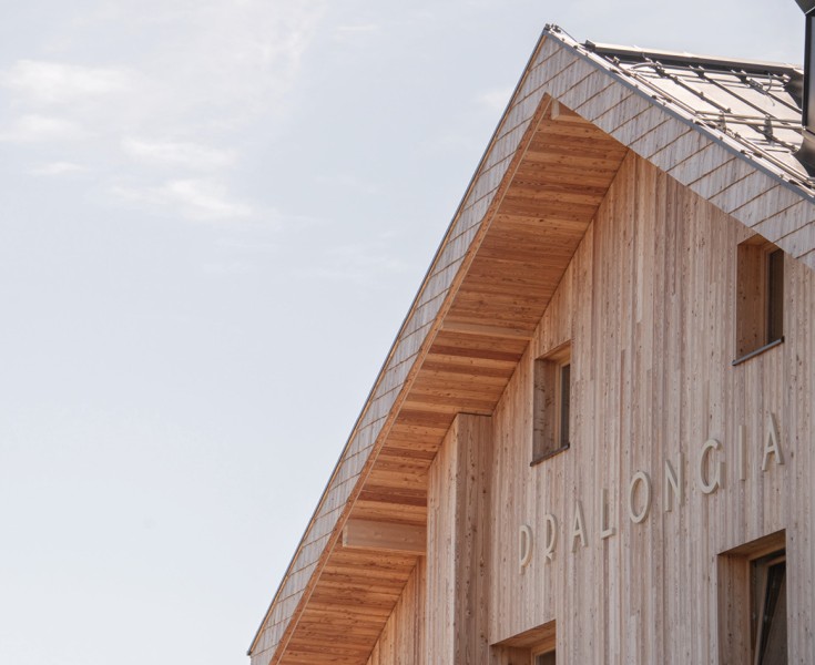 Primo piano del piano superiore e del tetto rivestiti in legno del rifugio alpino recentemente ristrutturato con la scritta Pralongià.