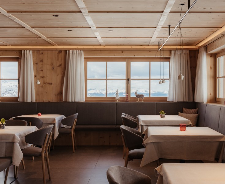 L'accogliente sala da pranzo con diversi tavoli e una vetrata crea un'atmosfera piacevole.