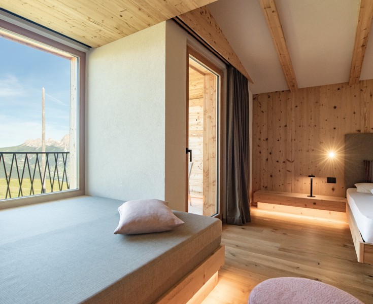 Una stanza in cui tutto è stato realizzato in legno. Le pareti, il pavimento, il letto. Una generosa vetrata porta molta luce nella stanza e permette una vista fantastica sulle Dolomiti.
