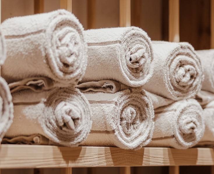 Fila di asciugamani arrotolati su una mensola di legno.