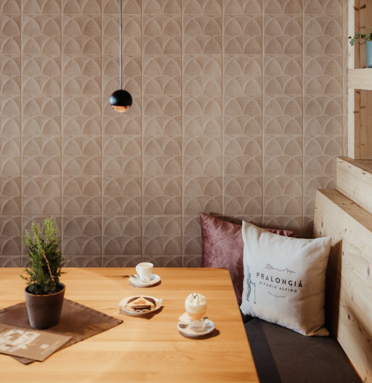 Un tavolo di legno vero nell'angolo, fatto di legno di pino cembro, crea un'atmosfera accogliente e sembra invitante. Sul tavolo ci sono due bicchieri di gustoso Bombardino.