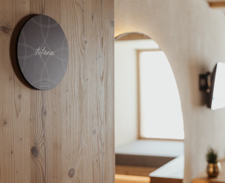 Parete in legno in una delle camere, con una targa recante la scritta Tofana.