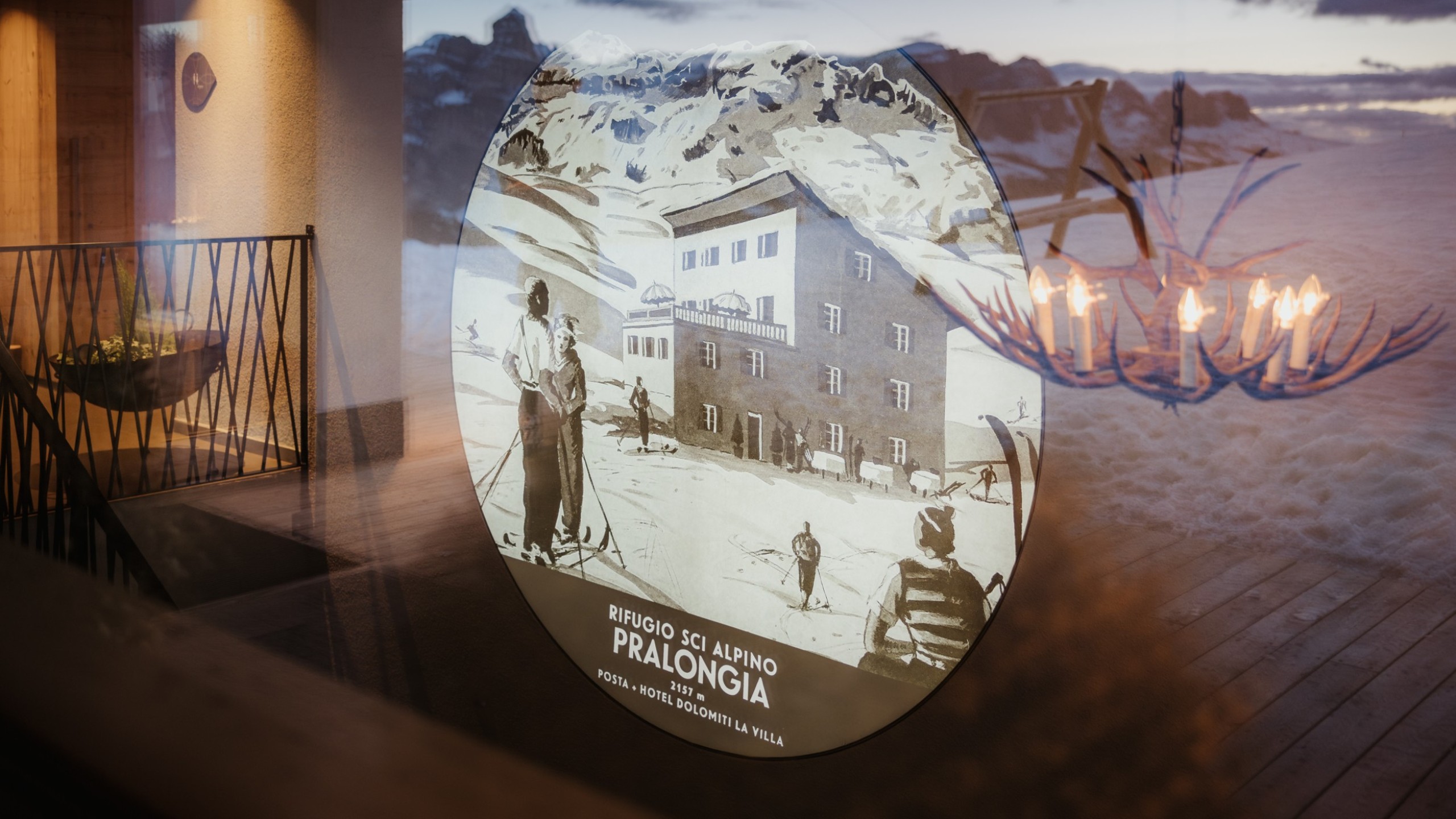 A painted, round picture on a wall shows the old Pralongià mountain inn as it used to be. In the foreground are illustrated skiers.