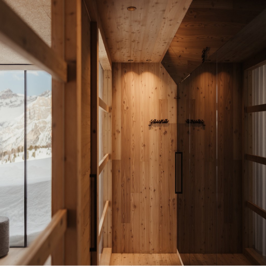 Holzwand mit dem Schriftzug sauna und durch einer Glastür Blick nach draußen auf verschneite Berge.