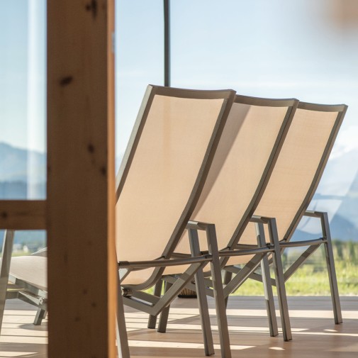 Tre comode sedie a sdraio su una terrazza con una vetrata illuminata dal sole.