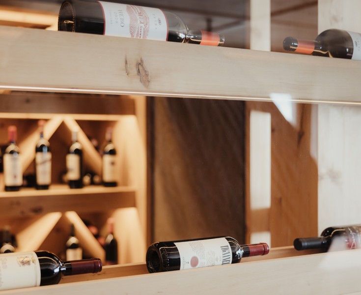 Una scaffalatura per vini in legno che mostra diverse bottiglie di vino, presentata con stile e funzionalità.