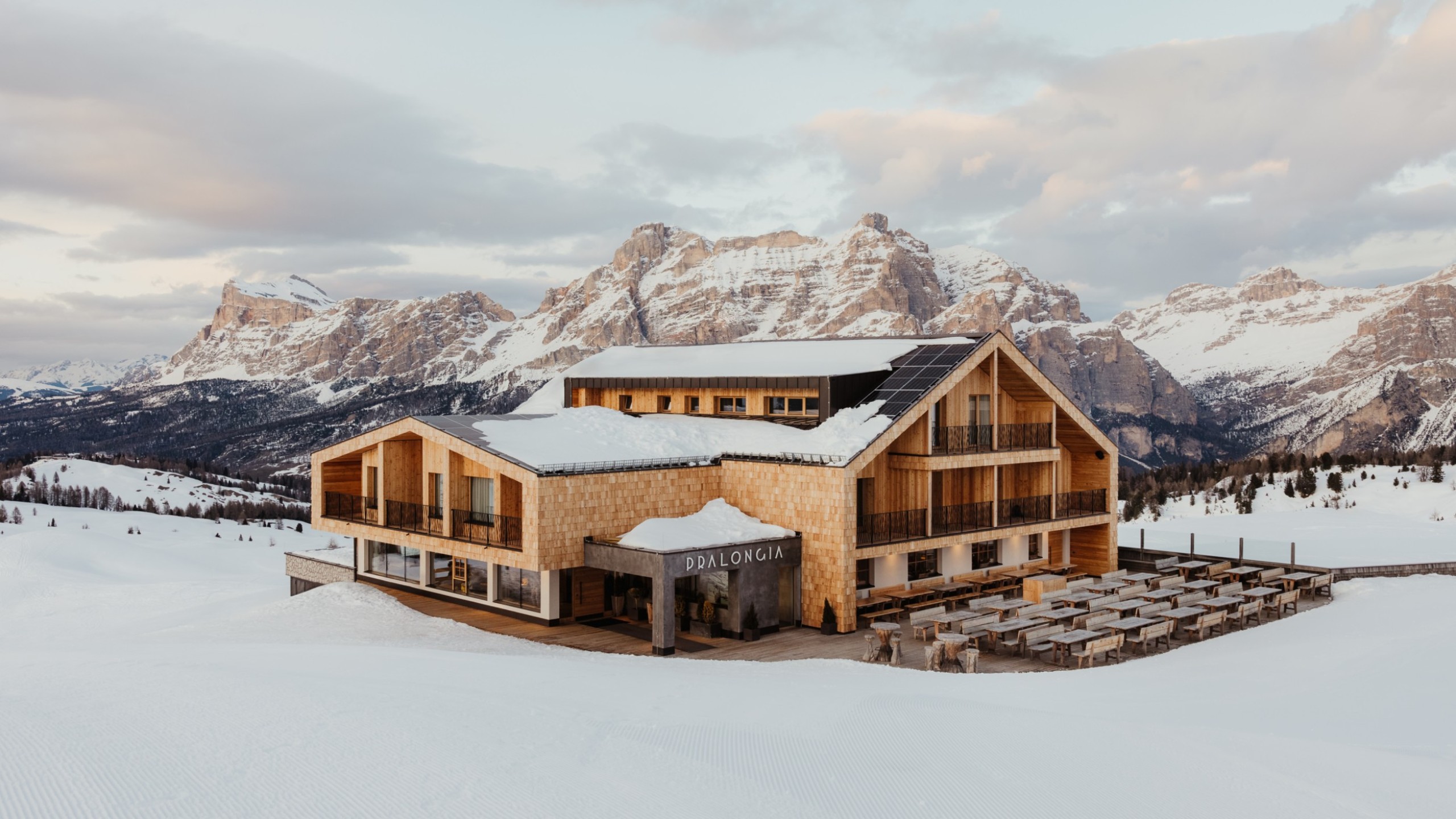 Das neu renovierte Berggasthaus Pralongià im Winter, mit verschneiten Bergen im Hintergrund.