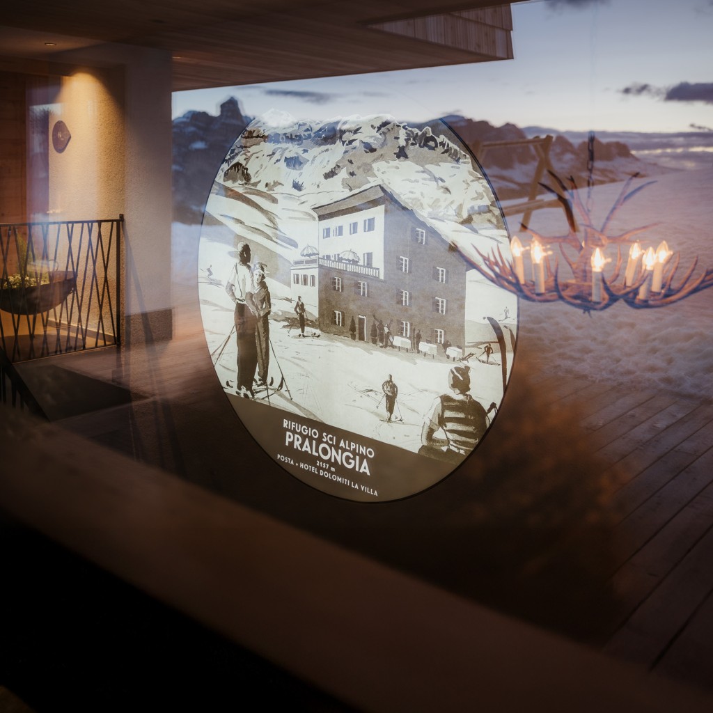 A painted, round picture on a wall shows the old Pralongià mountain inn as it used to be. In the foreground are illustrated skiers.
