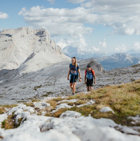 Eine Frau und ein Mann wandern in den Dolomiten auf einem steinigen Weg.