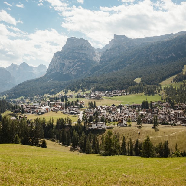 Das Dorf Stern aus der Ferne, umgeben von viel Wald und Wiese, Bergpanorama im Hintergrund.